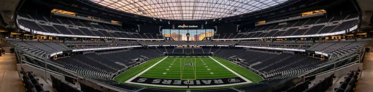 Inside Allegiant Stadium looking across the football field toward the iconic Lanai glass doors with the Las Vegas Strip visible beyond