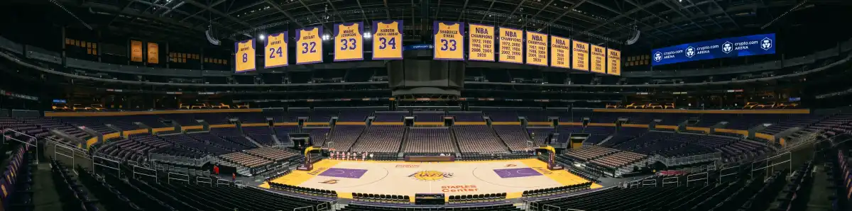 Inside Crypto.com Arena looking across the basketball court with Lakers championship banners hanging from the rafters