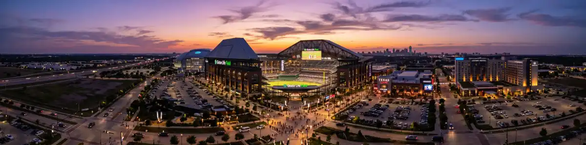 Arlington Entertainment District at dusk with hotel buildings illuminated and Globe Life Field visible in the background