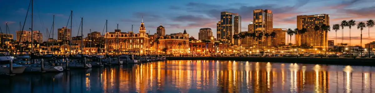 San Diego Gaslamp Quarter skyline at dusk with hotel buildings, harbor views, and palm trees illuminated