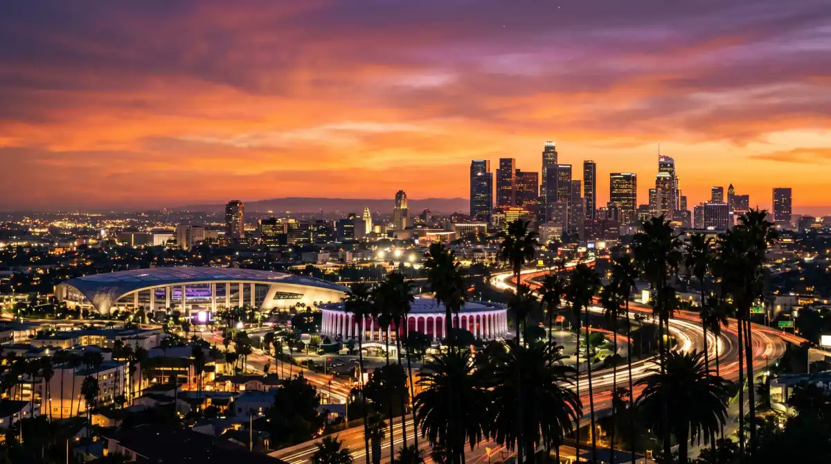 Los Angeles skyline at dusk with hotel buildings illuminated and palm tree silhouettes